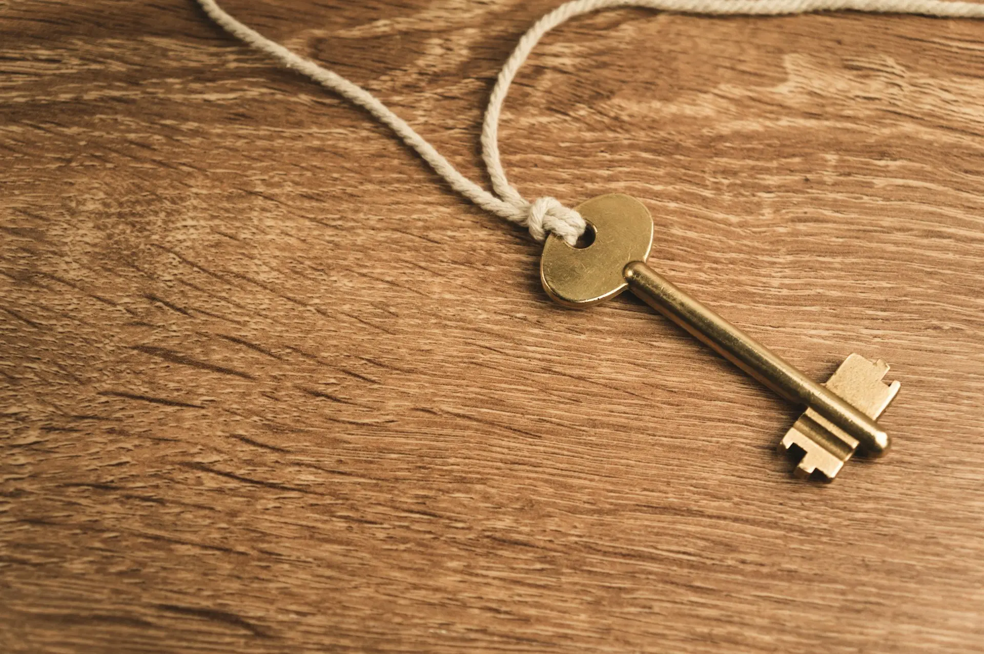 a golden key on a string on a wooden surface